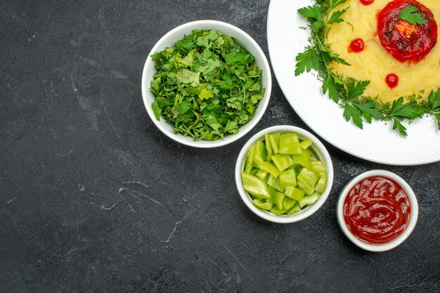 Bovenaanzicht van aardappelpuree met groenten en tomatensaus op donker