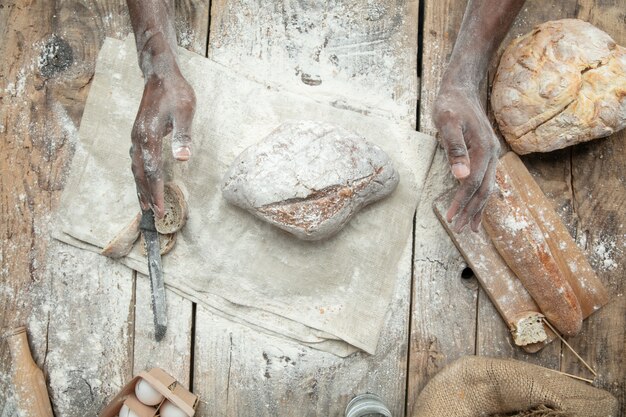 Bovenaanzicht van Afro-Amerikaanse man kookt vers ontbijtgranen, brood, zemelen op houten tafel