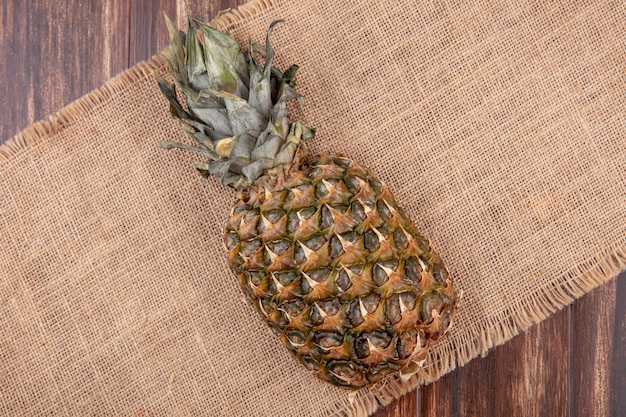 Bovenaanzicht van ananas op zak en houten oppervlak