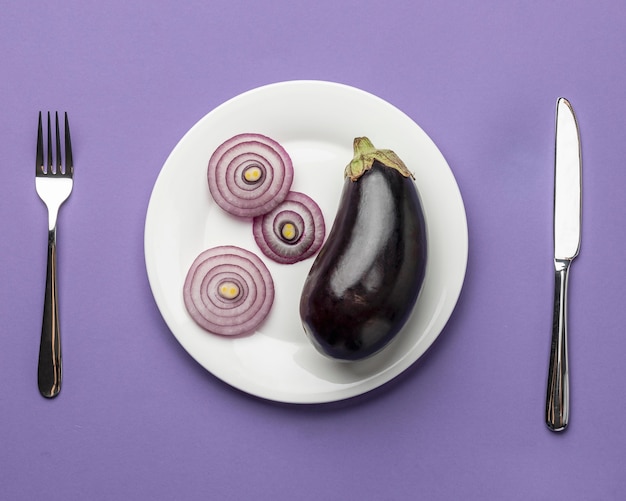 Gratis foto bovenaanzicht van aubergine en ui op plaat met bestek