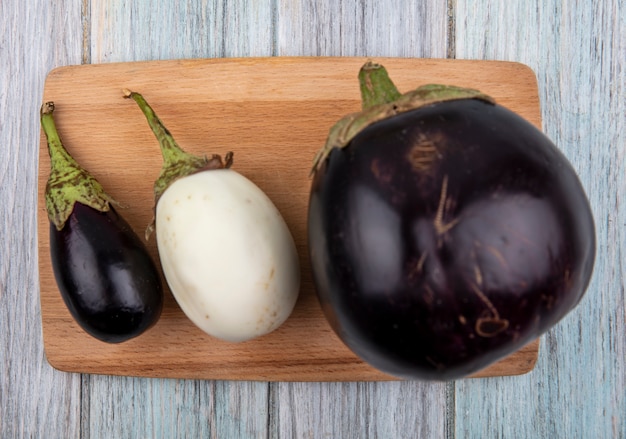 Bovenaanzicht van aubergines op snijplank op houten achtergrond