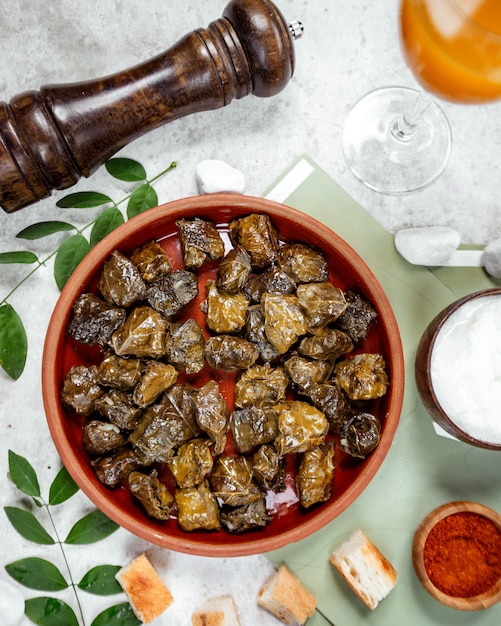 Gratis foto bovenaanzicht van azerbeidzjan druivenbladeren dolma in aardewerk pan geserveerd met yoghurt