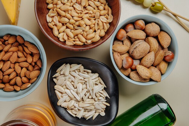 Bovenaanzicht van bier snacks mix van noten zonnebloempitten en gezouten pinda's met een flesje bier op wit