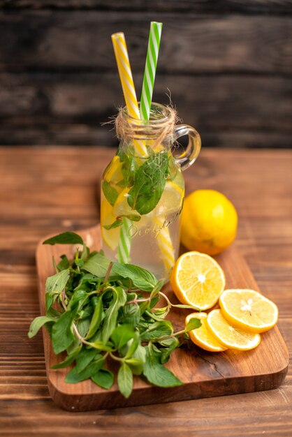 Bovenaanzicht van biologisch natuurlijk vers detoxwater geserveerd met buisjes munt en sinaasappel op een snijplank op een houten tafel