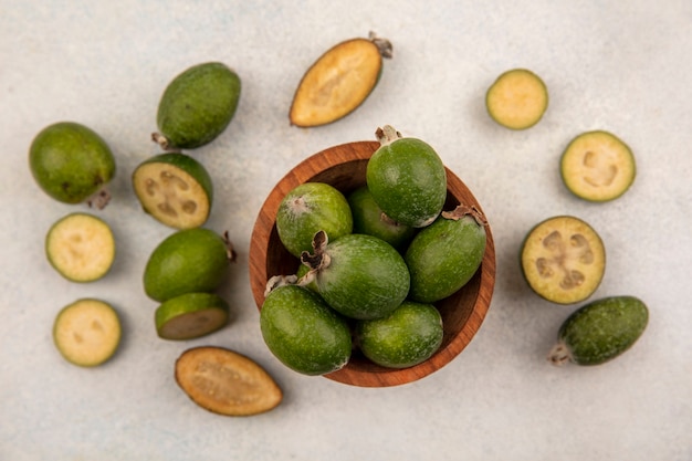 Bovenaanzicht van biologische en gezonde feijoas op een houten kom met feijoas geïsoleerd op een grijs oppervlak