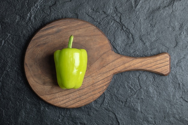 Gratis foto bovenaanzicht van biologische groene peper op een houten bord op zwarte achtergrond.