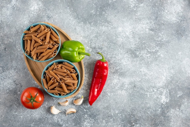 Bovenaanzicht van biologische groenten met rauwe penne pasta.