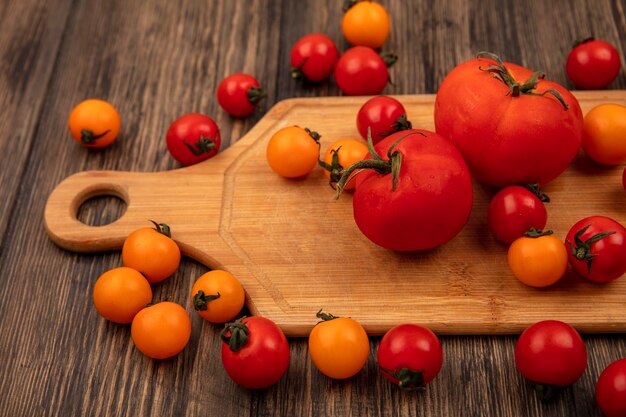 Bovenaanzicht van biologische oranje en rode tomaten geïsoleerd op een houten keukenbord op een houten oppervlak