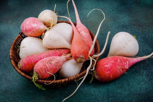 Bovenaanzicht van biologische witte en rozerode knolgewas bieten op een emmer op een groene achtergrond