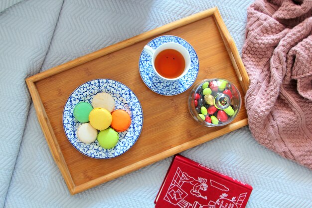 Bovenaanzicht van bitterkoekjes op een bord geserveerd met thee op een houten dienblad