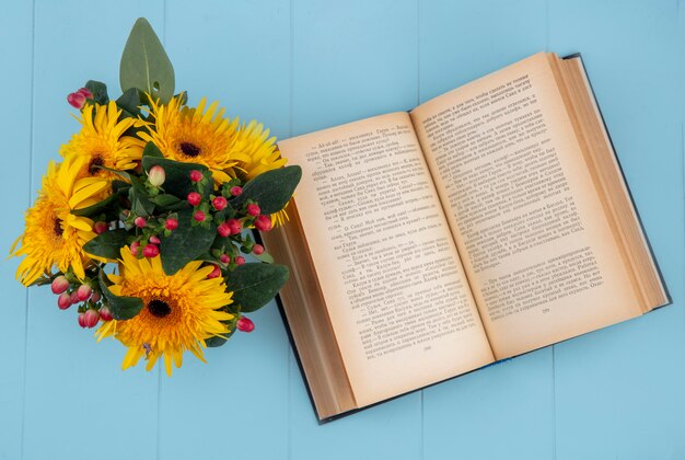 Bovenaanzicht van bloemen op open boek op blauw