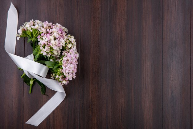 Gratis foto bovenaanzicht van boeket van wilde bloemen met wit lint op een houten oppervlak