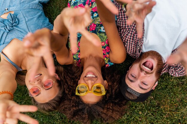 Bovenaanzicht van bovenaf op kleurrijke stijlvolle gelukkig jong gezelschap van vrienden liggend op gras in park, man en vrouw samen plezier