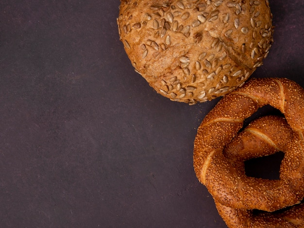 Bovenaanzicht van brood als geplaatste maïskolf en Turks bagel aan de rechterkant en kastanjebruine achtergrond met kopie ruimte