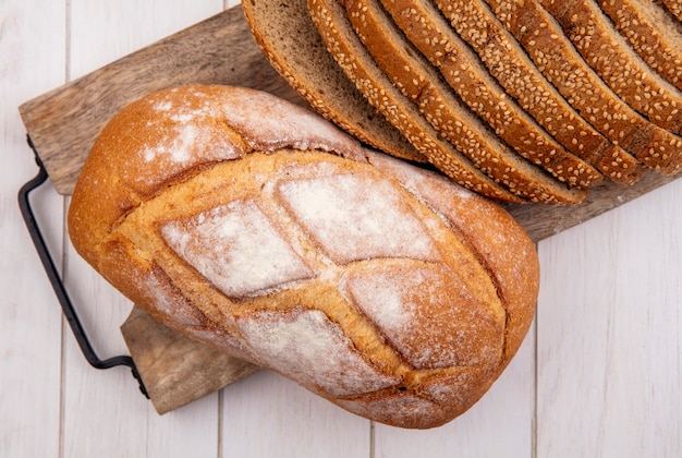 Bovenaanzicht van brood als gesneden bruin geplaatste kolf en knapperig brood op snijplank op houten achtergrond