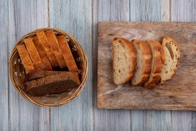 Bovenaanzicht van brood als gesneden rogge stokbrood en knapperige degenen op snijplank en in mand op houten achtergrond