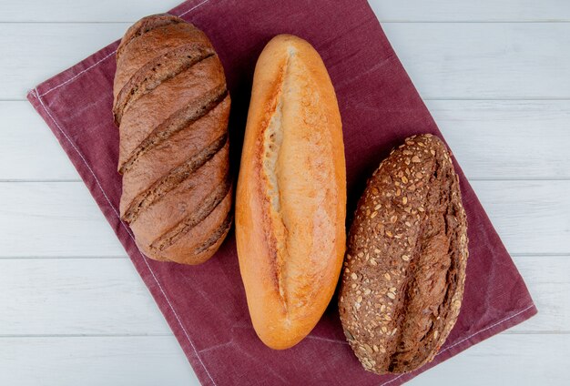 Bovenaanzicht van brood als Vietnamees en zwart zaad stokbrood en zwart brood op bordo doek en houten tafel