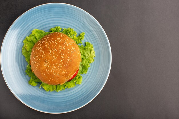 Bovenaanzicht van broodje kip met groene salade en groenten in plaat op het donkere oppervlak