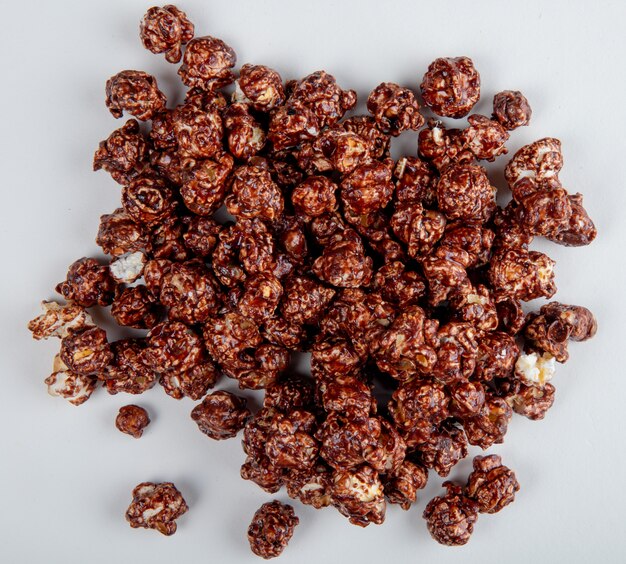 Bovenaanzicht van chocolade popcorn op wit