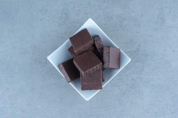 Bovenaanzicht van chocoladewafels in witte kom.