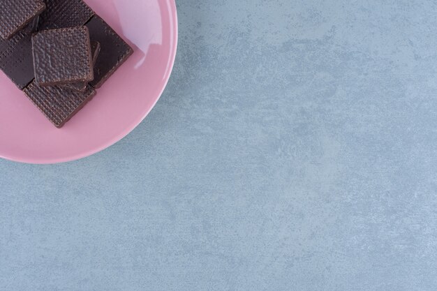 Bovenaanzicht van chocoladewafels op roze plaat. Op de hoek van de foto.