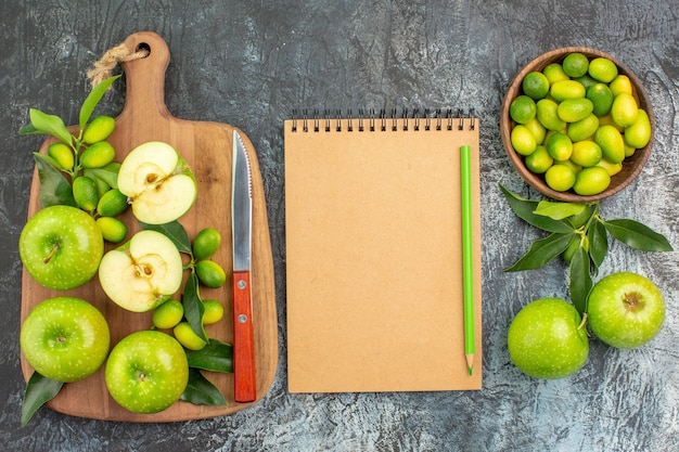 Bovenaanzicht van close-up fruit de smakelijke appels mes op het bord citrusvruchten notebook potlood