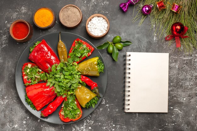 Bovenaanzicht van close-up paprika's witte notebook plaat van paprika's Kerstboom speelgoed kleurrijke kruiden