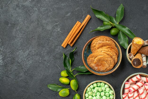 Bovenaanzicht van close-up snoep snoepjes kaneelstokjes citrusvruchten met bladeren wafels cookies