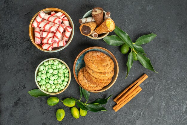 Bovenaanzicht van close-up snoepjes citrusvruchten met bladeren kaneel kleurrijke snoepjes wafels koekjes