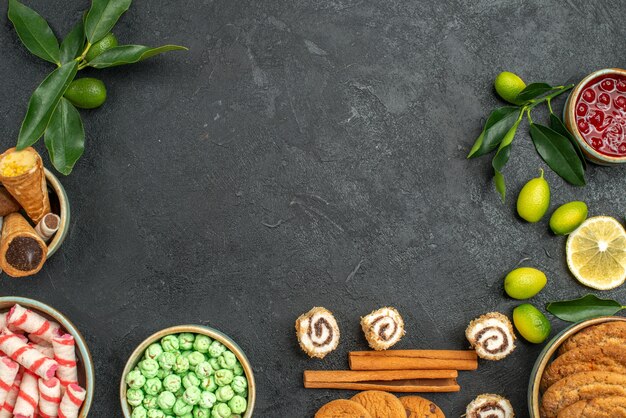 Bovenaanzicht van close-up snoepjes wafels koekjes kleurrijke snoepjes jam kaneel citrusvruchten met bladeren