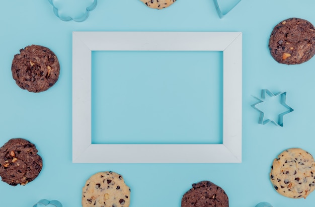 Bovenaanzicht van cookies rond frame op blauwe achtergrond met kopie ruimte