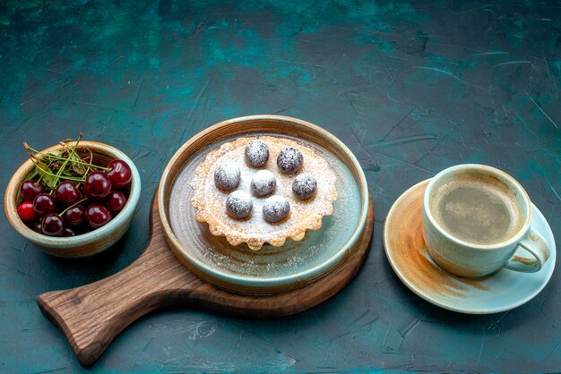 Bovenaanzicht van cupcake met lekkere kersen naast latte op donkerblauw,