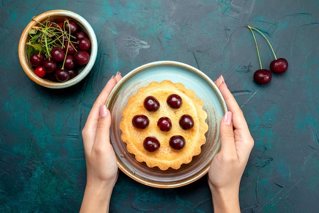 Gratis foto bovenaanzicht van cupcake met versierde kersen die iemand het op tafel zette