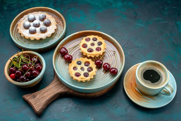 Bovenaanzicht van cupcakes met ronde kersen naast americano