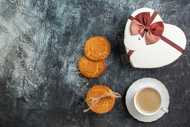 Bovenaanzicht van de beste verrassing met een mooie geschenkdoos en een kopje koffiekoekjes voor de geliefde op een ijzig donker oppervlak