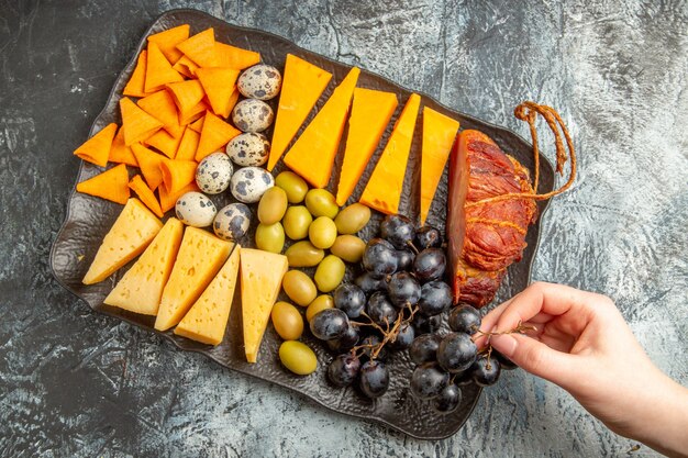 Bovenaanzicht van de hand die een van de voedingsmiddelen uit de heerlijke beste snack voor wijn neemt op een bruin dienblad op een ijsachtergrond