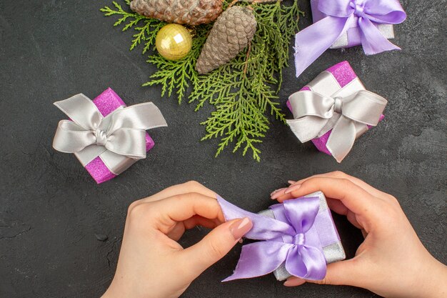 Bovenaanzicht van de hand met een van de kleurrijke geschenken en decoratieaccessoires op een donkere achtergrond