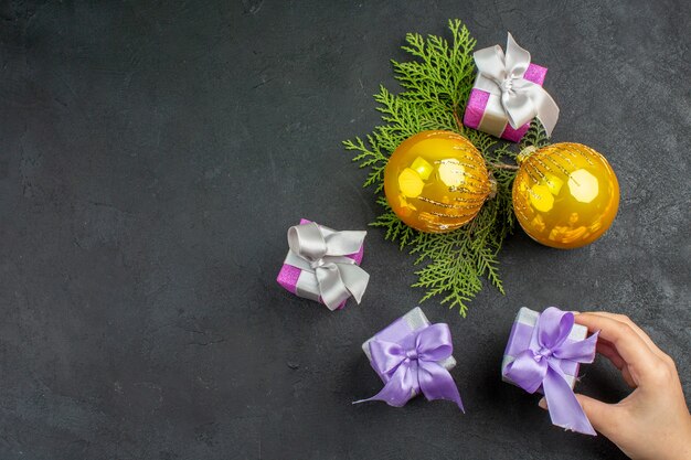 Bovenaanzicht van de hand met een van de kleurrijke geschenken en decoratieaccessoires op een donkere achtergrond