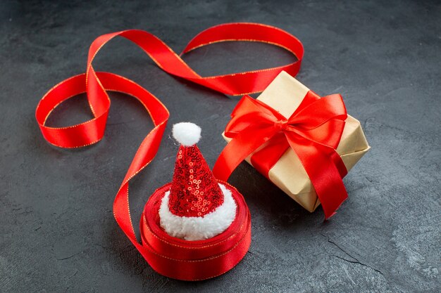 Bovenaanzicht van de kerstman hoed op een rol lint en mooi cadeau op donkere achtergrond
