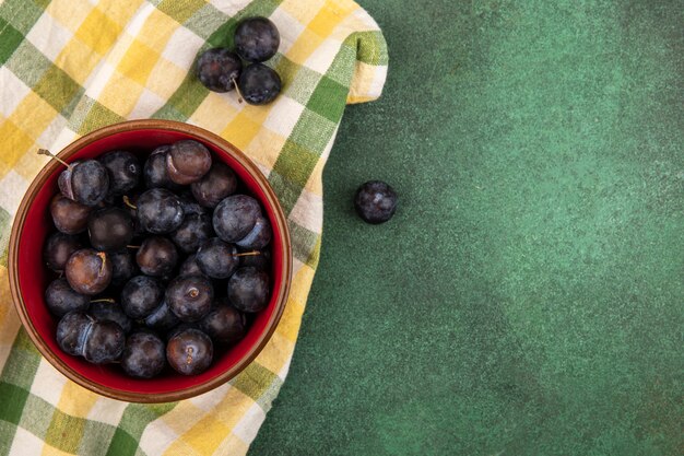 Bovenaanzicht van de kleine zure blauwzwarte fruitslaesjes op een geruit tafelkleed op een groene achtergrond met kopie ruimte