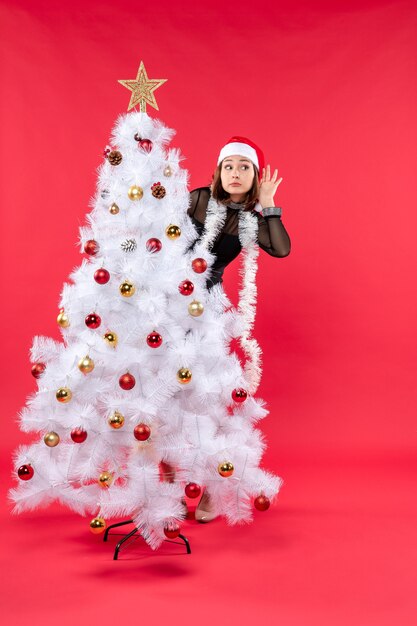 Bovenaanzicht van de stemming van het nieuwe jaar met lachende mooi meisje in een zwarte jurk met kerstman hoed