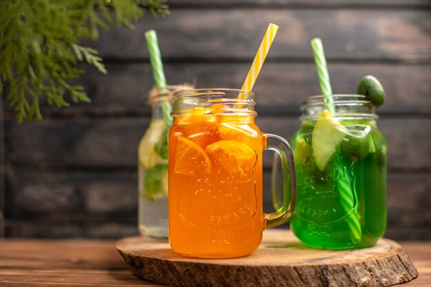 Bovenaanzicht van detox water en vers sap in flessen met buizen aan de linkerkant op bruin houten achtergrond