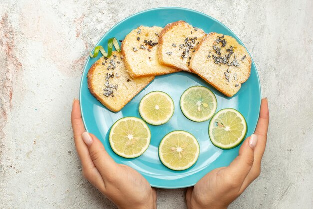 Bovenaanzicht van dichtbij brood en citroenblauw bord met gesneden citroen en wit brood in de hand