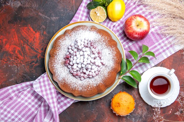 Bovenaanzicht van dichtbij een cake een cake een kopje thee citrusvruchten op het tafelkleed appelbladeren