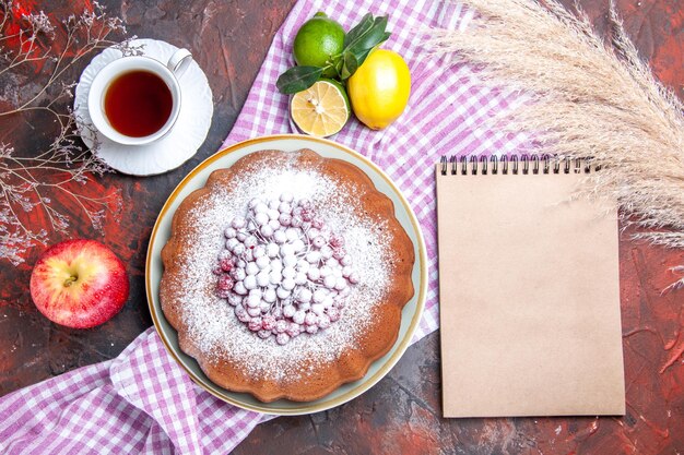 Bovenaanzicht van dichtbij een cake een cake met bessen een kopje thee citrusvruchten notitieboekje tarweoren