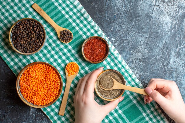 Bovenaanzicht van dinerbereiding met verschillende paprika's en gele erwt op groene gestripte handdoek op grijze achtergrond