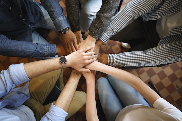 Bovenaanzicht van diverse mensenhanden die samen in de stapel van cirkelhanden houden