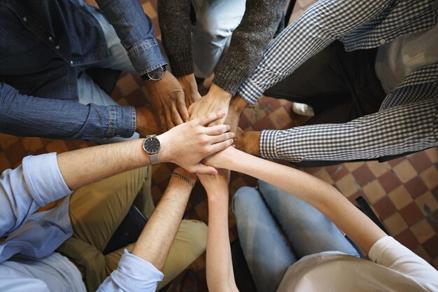 Bovenaanzicht van diverse mensenhanden die samen in de stapel van cirkelhanden houden