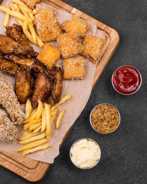 Bovenaanzicht van diverse sauzen met frietjes en gebakken kip