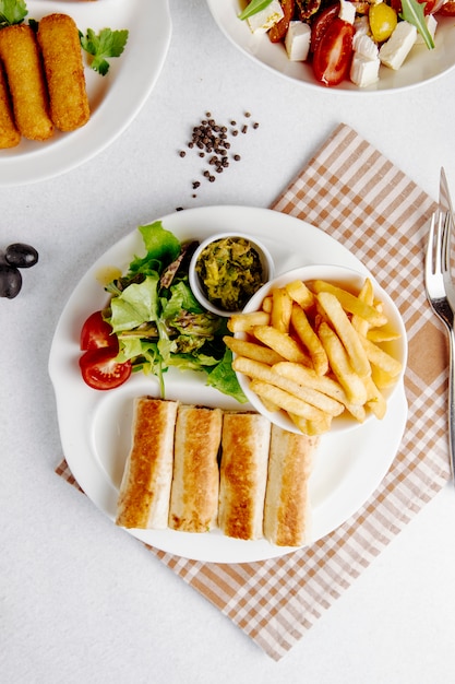 Bovenaanzicht van doner in lavash met frietjes en verse salade op plaat